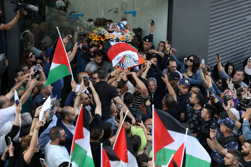 Palestinians carry the flag-draped body of veteran Al-Jazeera journalist Shireen Abu Akleh as it is carried toward the offices of the news channel in the West Bank city of Ramallah, on May 11, 2022. (Photo: Wajed Nobani/APA Images)