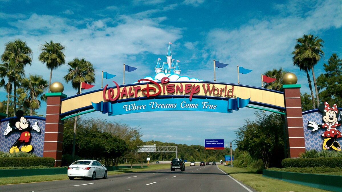 Walt Disney World Resort entrance sign with cars driving under it