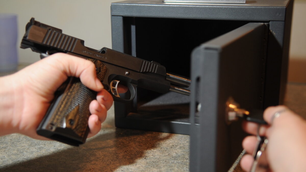 person placing a gun into a safe